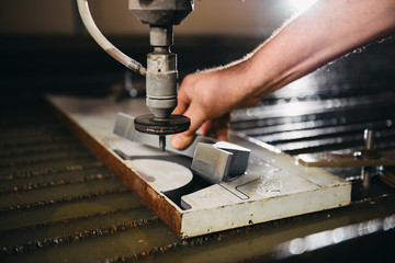 Worker at water jet cutter takes out cut section