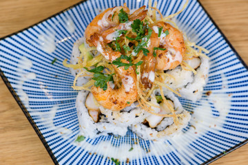 pyramid of maki roll with fried shrimps, tempura vegetables, sesame and rocket decoration