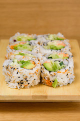 sushi roll with zucchini, crab meat, salad, avocado and carrots, covered with caviar, black and white sesame