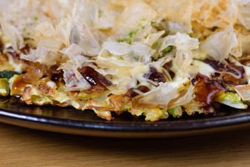 Japanese omelette Okonomiyaki, with eggs, Savoy cabbage, mayonnaise, carrot, zucchini, ginger, dried seaweed and Katsuobushi, okaka, flakes of dried meat from skipjack tuna