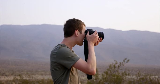 Young stylish male photographer takes photo on desert highway - care free adventure