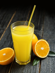 Fresh cold orange juice on dark wooden background