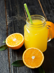 Fototapeta na wymiar Fresh cold orange juice on dark wooden background