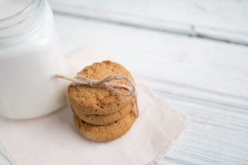 Glass of milk and cookies on a wooden white table
