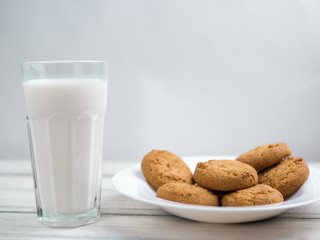 Glass of milk and cookies on a wooden white table