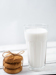 Glass of milk and cookies on a wooden white table