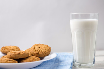 Glass of milk and cookies on a wooden white table