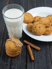 Oatmeal cookies with milk on wooden background