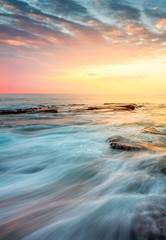 Incoming waves wash over rocks at sunrise