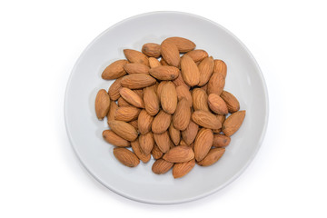 Top view of almonds peeled from shells on white saucer
