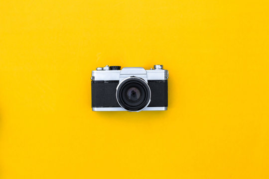 Flat lay black vintage camera and film on yellow paper background