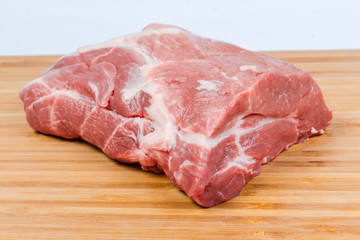 Uncooked pork neck on the wooden cutting board close-up