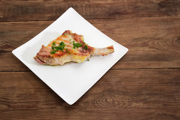 Grilled pork loin on bone on dish on rustic table