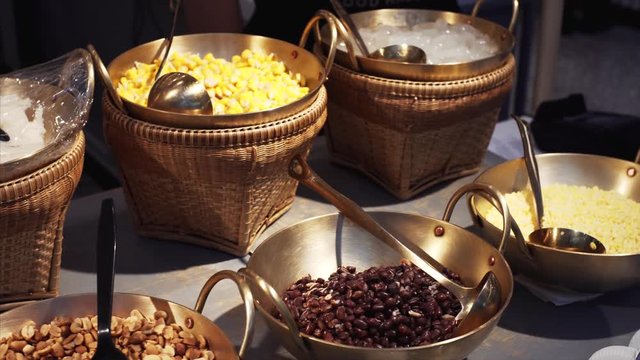 Bowls with corn, red kidney beans, peanuts and other snacks in food court in Bangkok, Thailand