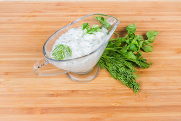 Mayonnaise sauce in glass gravy boat and fresh herbs