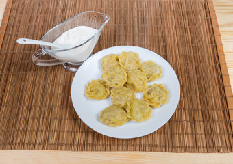 Cooked homemade meat dumplings and sauce on bamboo table mat
