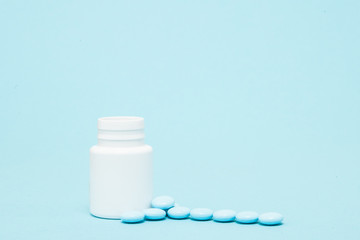 Blue pills and pill bottle on blue background