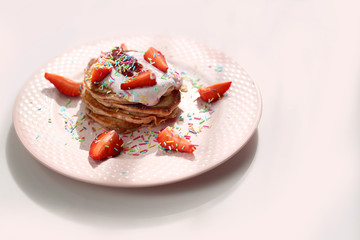 Pancakes with strawberries, cottage cheese and colorful sugar sprinkles.