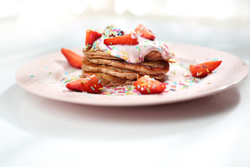 Pancakes with strawberries, cottage cheese and colorful sugar sprinkles.