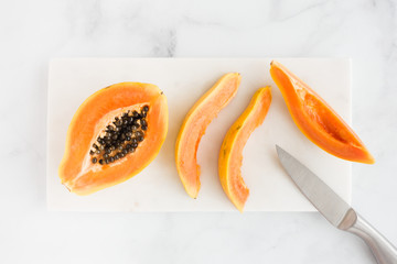 Closeup of Papaya Half and Slices on White Marble