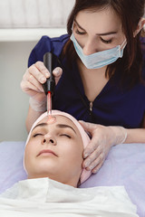 Anti-aging facial. Model receives physiotherapy, procedure of de-sonvalization. Beauty salon, cosmetology. Model and Doctor, close-up.