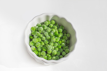 frozen green peas in bowl isolated on white