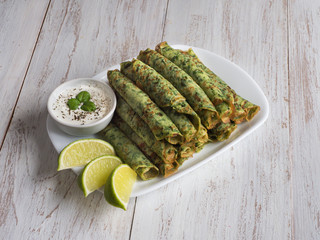 Spinach pancakes on a white wooden table. 