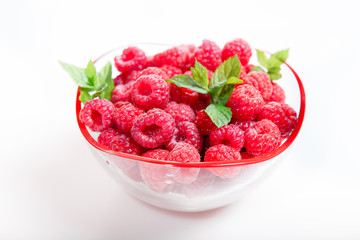 Ripe sweet raspberries in bowl on white. Close up, top view, high resolution product