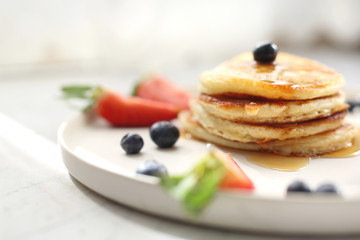 Pancakes with strawberries, blueberries and maple syrup. Sweet breakfast.