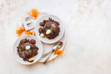 Easter cake with chocolate glaze, candies and  eggs on top  served on plate , textured surface, top view, copy space