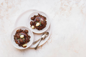 Easter nest chocolate cake decorated with chocolate curls and eggs on plate. Top view, blank space