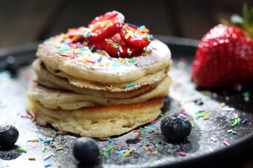 Fluffy pancakes with strawberries, blueberries and powdered sugar. 