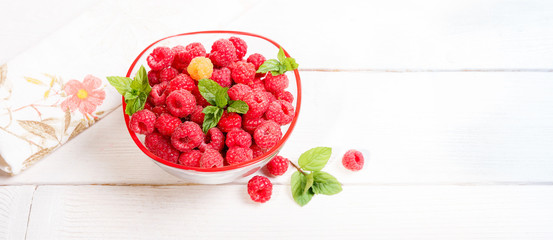 Ripe sweet raspberries in bowl on wooden table. Close up, top view, high resolution product