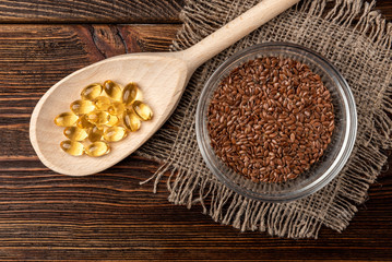 Fish oil and flax seeds on dark wooden background.