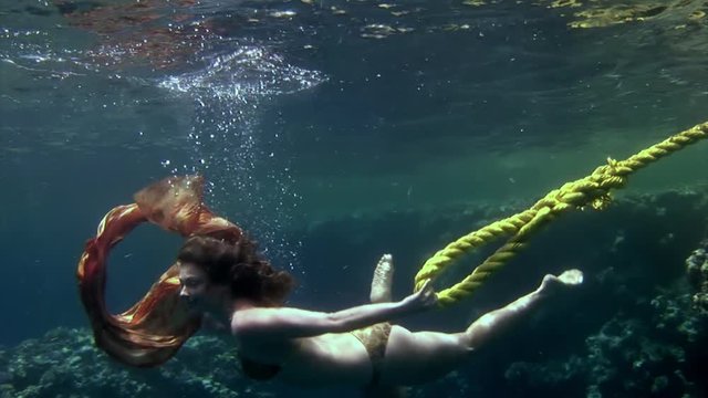 Cameraman shoots video young woman underwater model. Creativity and art of creating images on background of seabed.