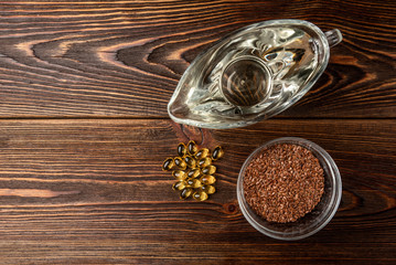 Fish oil, sunflower oil, and flax seeds on dark wooden background.