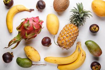 Tropical fruits on white. Dragon fruit, mango, pineapple, mangosteen, banana, coconut. Healthy food background. Summer concept. Top view, flat lay.