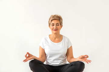 stylish elderly woman doing yoga on a white background
