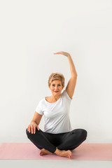stylish elderly woman doing yoga on a white background