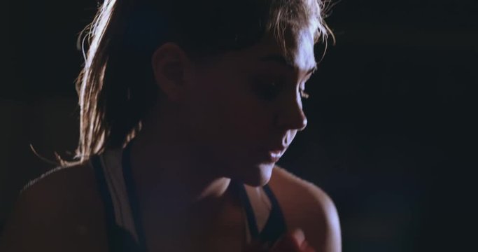A strong athletic, woman boxer, boxing at training on the black background. Sport boxing Concept with copy space.