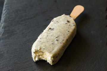 Ice cream lolly with white chocolate coating and dark chocolate cookie crumbs isolated on black background