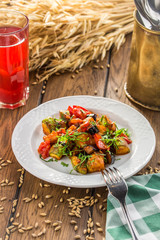 Grilled vegetables warm salad with zucchini, eggplant, onions, peppers and tomato with berry juice on wooden table