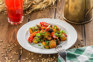 Grilled vegetables warm salad with zucchini, eggplant, onions, peppers and tomato with berry juice on wooden table