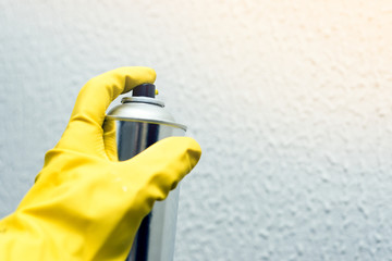 painting the walls of the spray. hand in yellow rubber gloves holding spray paint. repairs.