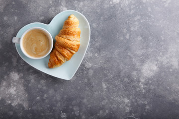 Cup of coffee and freshly baked croissants on gray background. Top view. Copy space.