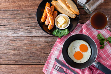 Breakfast with fried eggs on pan and sausage grill with toast, coffee on table, Healthy homemade meal. Top view and Copy space.