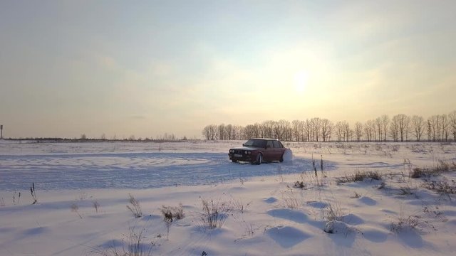 Red retro car drift on a field in the snow