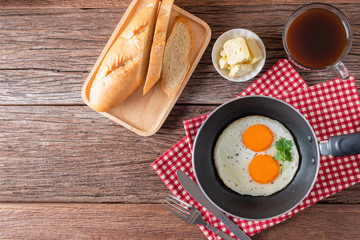 Breakfast with fried eggs on pan and bread with butter, hot coffee on table, Healthy homemade meal. Top view and Copy space.