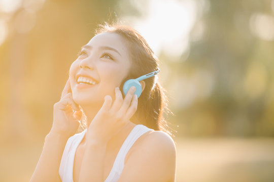 Beautiful Asian Woman Listening Music In The Park