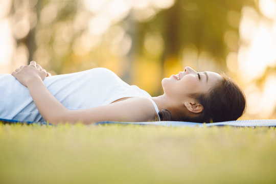 Beautiful Young Woman Laying On Grass In Park